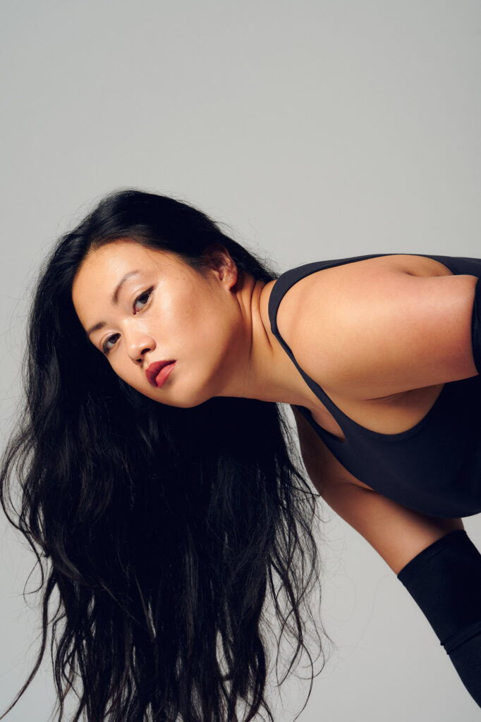 A model is leaning over with long, wavy black hair that is hanging down.