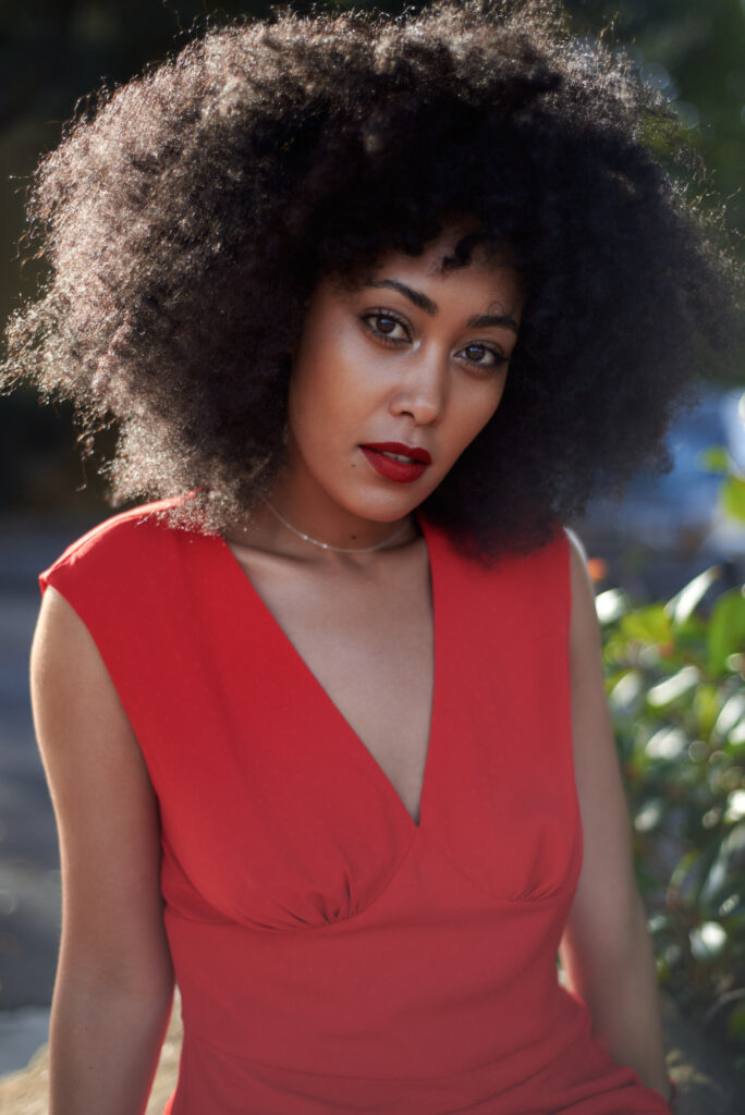 A model in a red dress with the sunlight shining from behind her